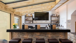Una zona de bar con pared de piedra, techo de madera y taburetes.