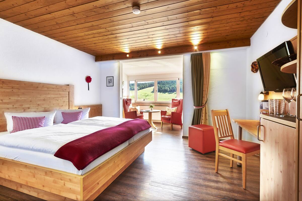 Une chambre avec un lit en bois, une télévision et un coin repas comprenant des chaises et une table.
