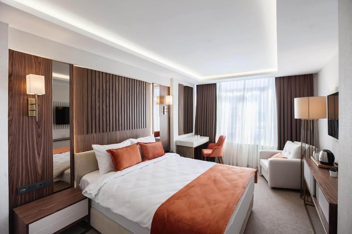 Ein modernes Hotelzimmer mit einem großen Bett, einem Schreibtisch, einem Stuhl und einem Fernseher.