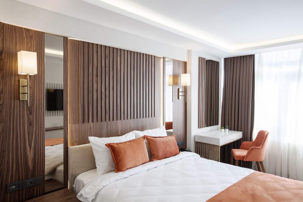 Ein modernes Hotelzimmer mit einem Bett, einem Schreibtisch, einem Stuhl und einem großen Spiegel.