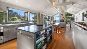 Una cucina moderna con una grande isola, pavimento in legno e ampie finestre con vista sull'esterno.