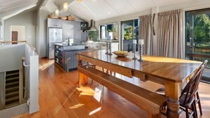 Una cucina moderna con isola centrale, pavimento in legno e illuminazione a sospensione.