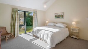 Una camera da letto con un letto grande, una sedia, un comodino e una finestra con tende.