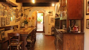 A cozy kitchen with wooden cabinets, a dining area with chairs, and a hallway leading to an open space.