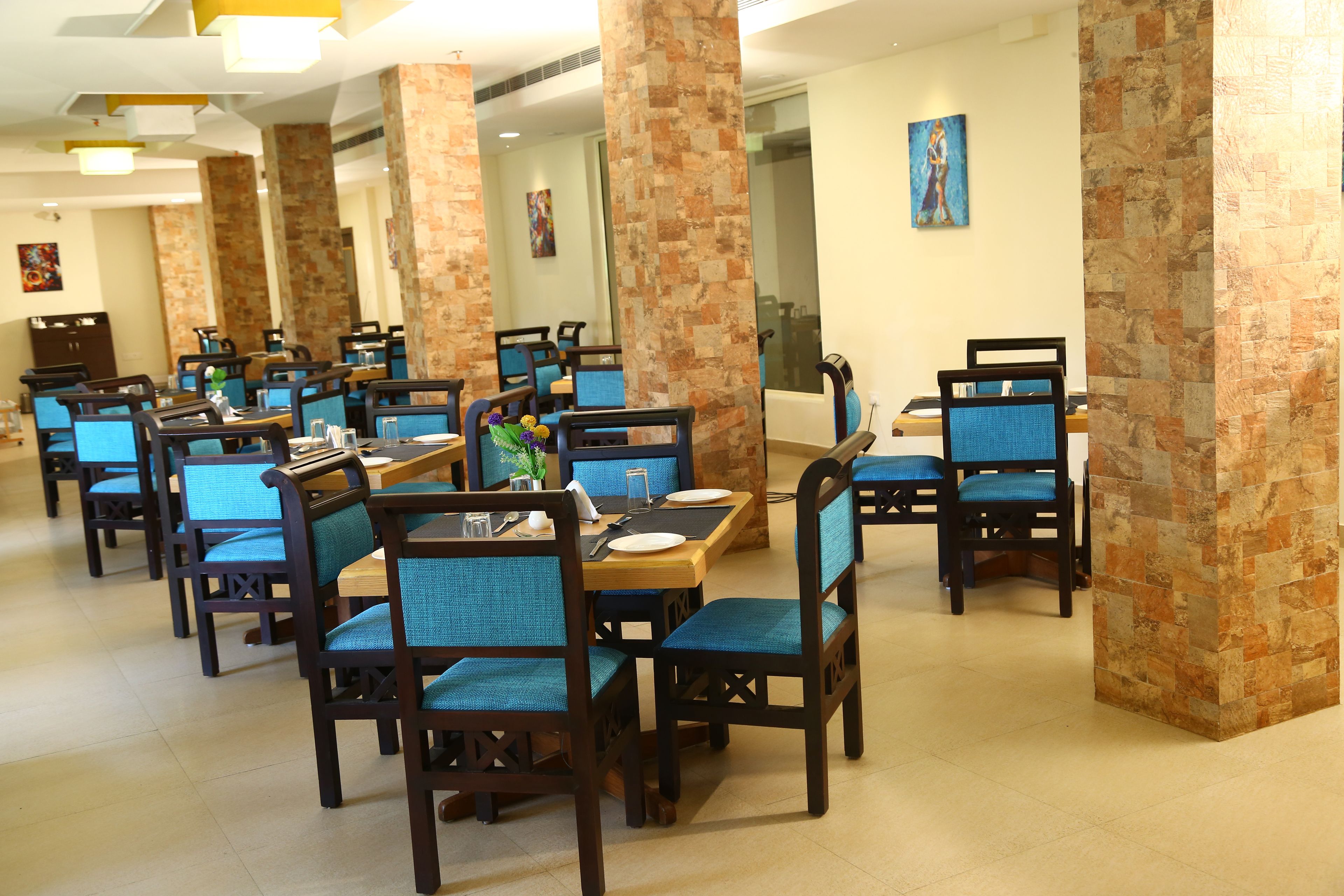 A dining area with multiple tables and chairs, featuring a mix of wooden and upholstered seating.