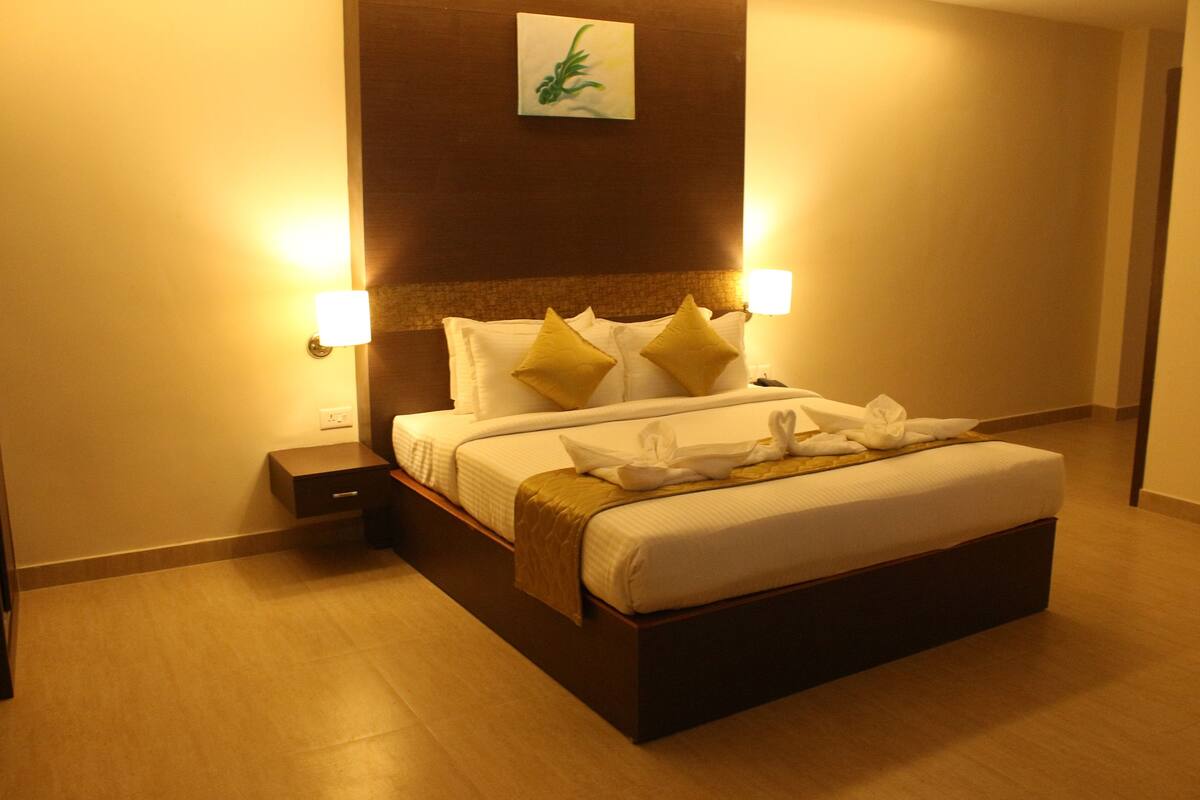 A hotel room with a large bed, two bedside lamps, a nightstand, and a painting on the wall.