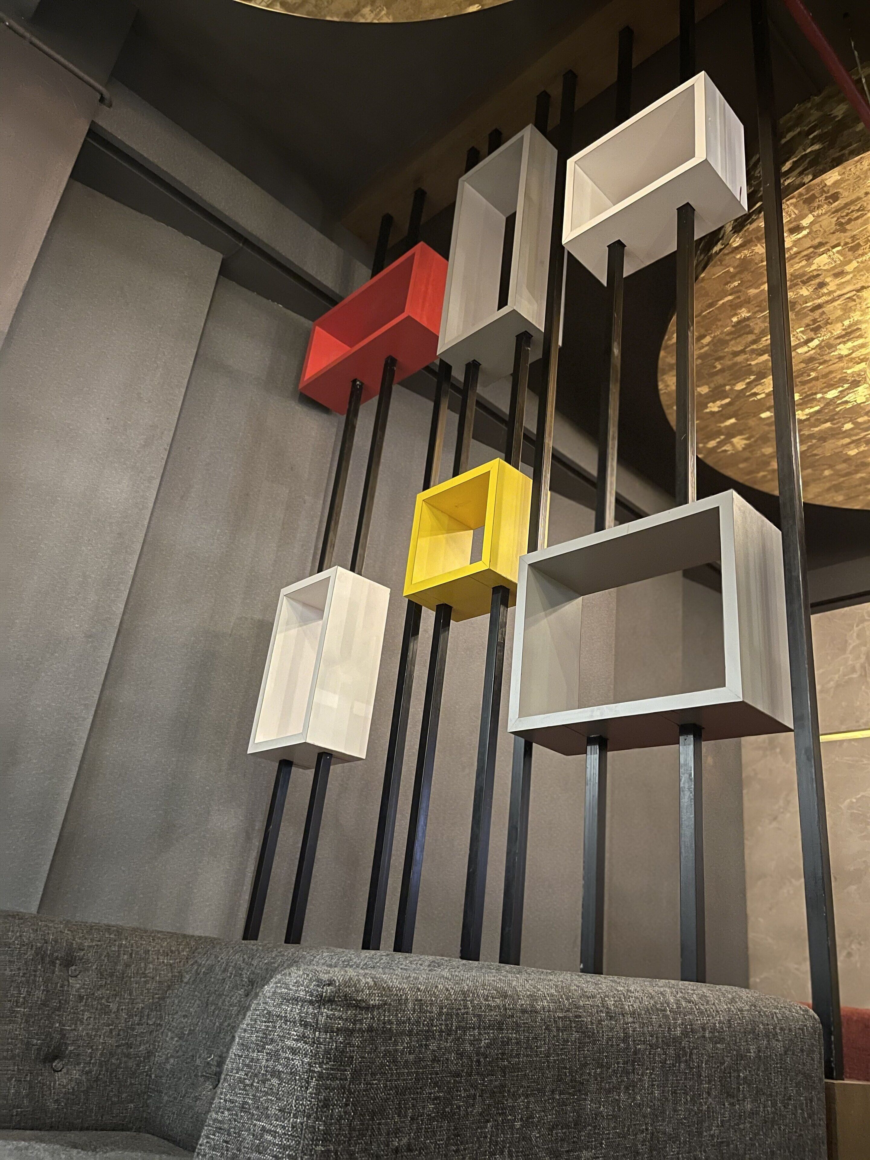 A modern interior with geometric shelving units in white, red, and yellow, mounted on black metal supports.