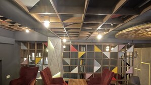 Un interior moderno con paneles geométricos en la pared, suelo de madera y sillones tapizados en rojo.