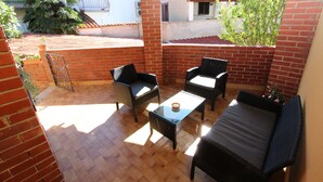 Eine Terrasse im Freien mit Backsteinmauern, einem Glastisch und Korbmöbeln.