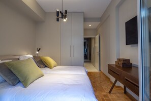 A bedroom with a bed, bedside tables, a wardrobe, and a desk. - Finesse Luxury Flat (Athens)