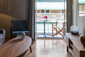 A modern living room with a sofa, a round table, and a chair. A vase with flowers is on the table. - Finesse Luxury Flat (Athens)