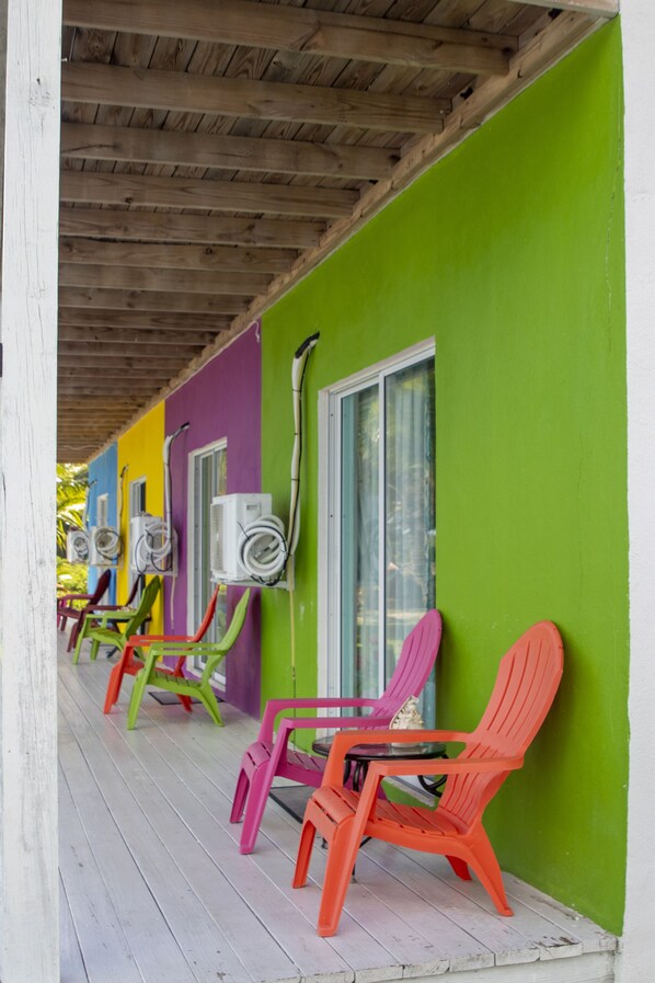 Un espacio al aire libre con techo, sillas de colores y unidades de aire acondicionado en la pared.