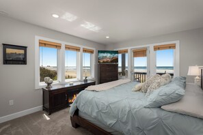 A bedroom with a large bed, a dresser, a TV, and a fireplace. - Amazing Oceanfront Home -Two Master Suites! (Rockaway Beach)