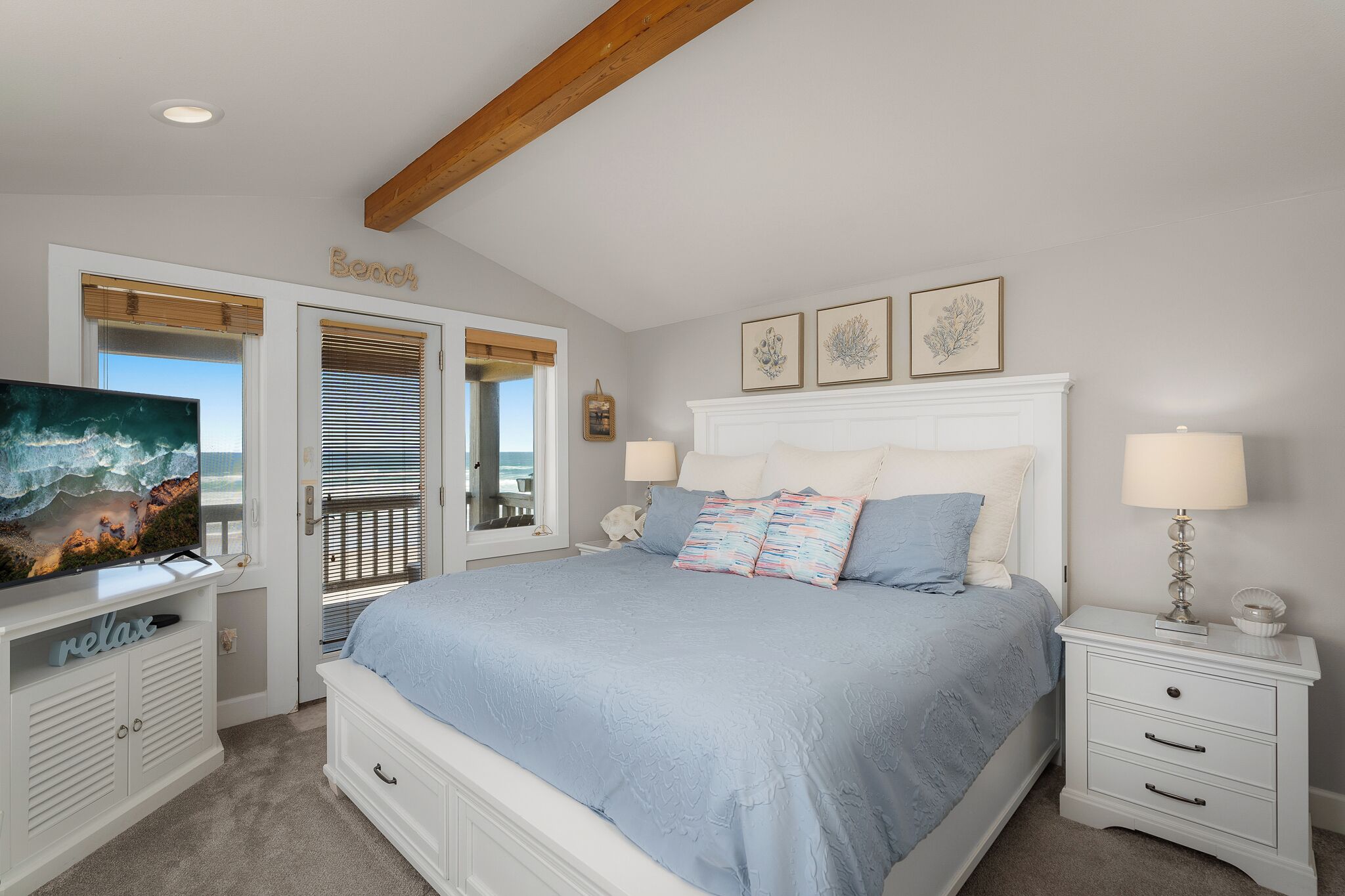 Une chambre avec un lit, une télévision, une table de chevet et une vue sur la plage.