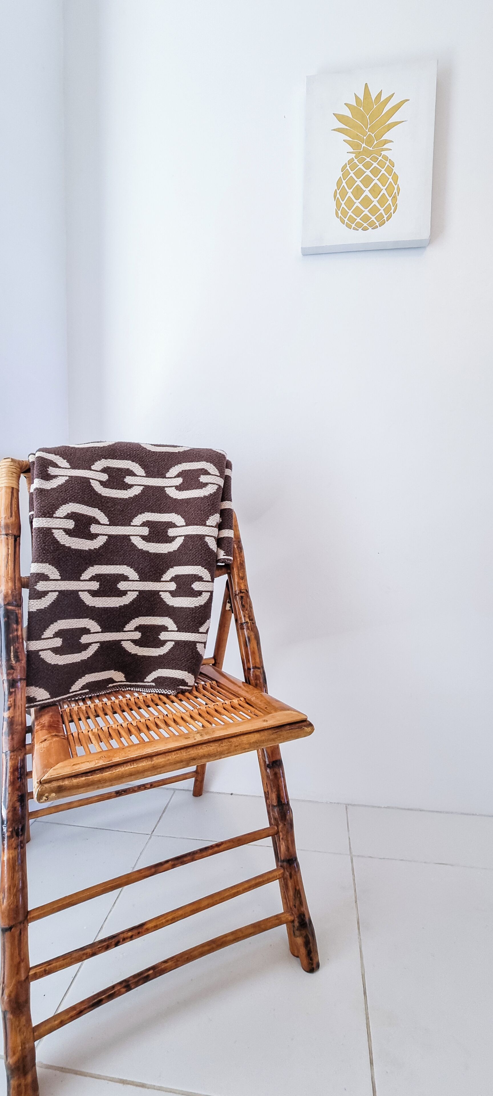 Une chaise en bois recouverte d’un plaid à motifs.