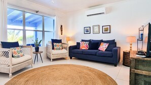 A living room with wicker furniture, a blue sofa, and a large window.