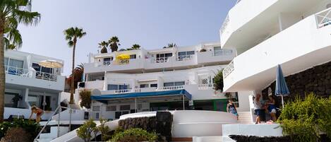 A resort with multiple white buildings, a pool area, and palm trees.