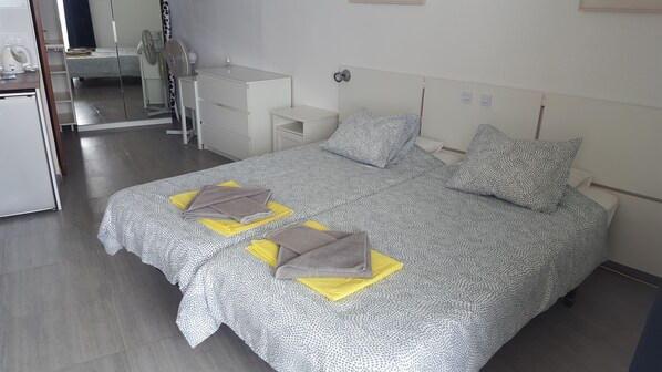 A neatly arranged hotel room with a large bed, a bedside table, a mirror, and a wardrobe. - Studio , southfacing sea views , own patio, 2 heated pools, overlooking harbour (Puerto del Carmen)