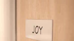 Una puerta de madera con una placa que dice "JOY" y un picaporte moderno.