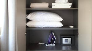 Habitación de hotel con cama, almohadas, una toalla doblada, microondas y toma de corriente.