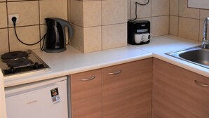 A kitchen with wooden cabinets, a coffee maker, a kettle, and a dishwasher. - Small & Cozy Flat near Hospitals (Zografos)