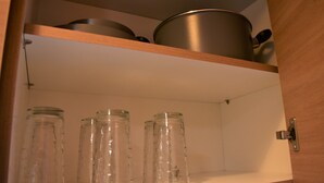A kitchen cabinet with stainless steel pots and glass jars. - Small & Cozy Flat near Hospitals (Zografos)