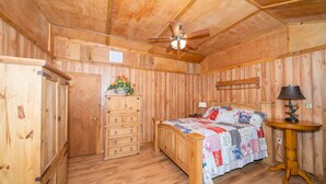 A wooden room with a bed, dresser, and ceiling fan.