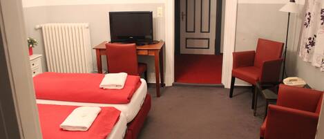 Una camera d'albergo con due letti, una scrivania con un computer, una sedia e un telefono.