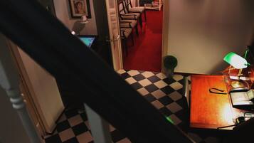 A staircase leading to a room with a checkered floor, a desk with a lamp, and striped chairs.