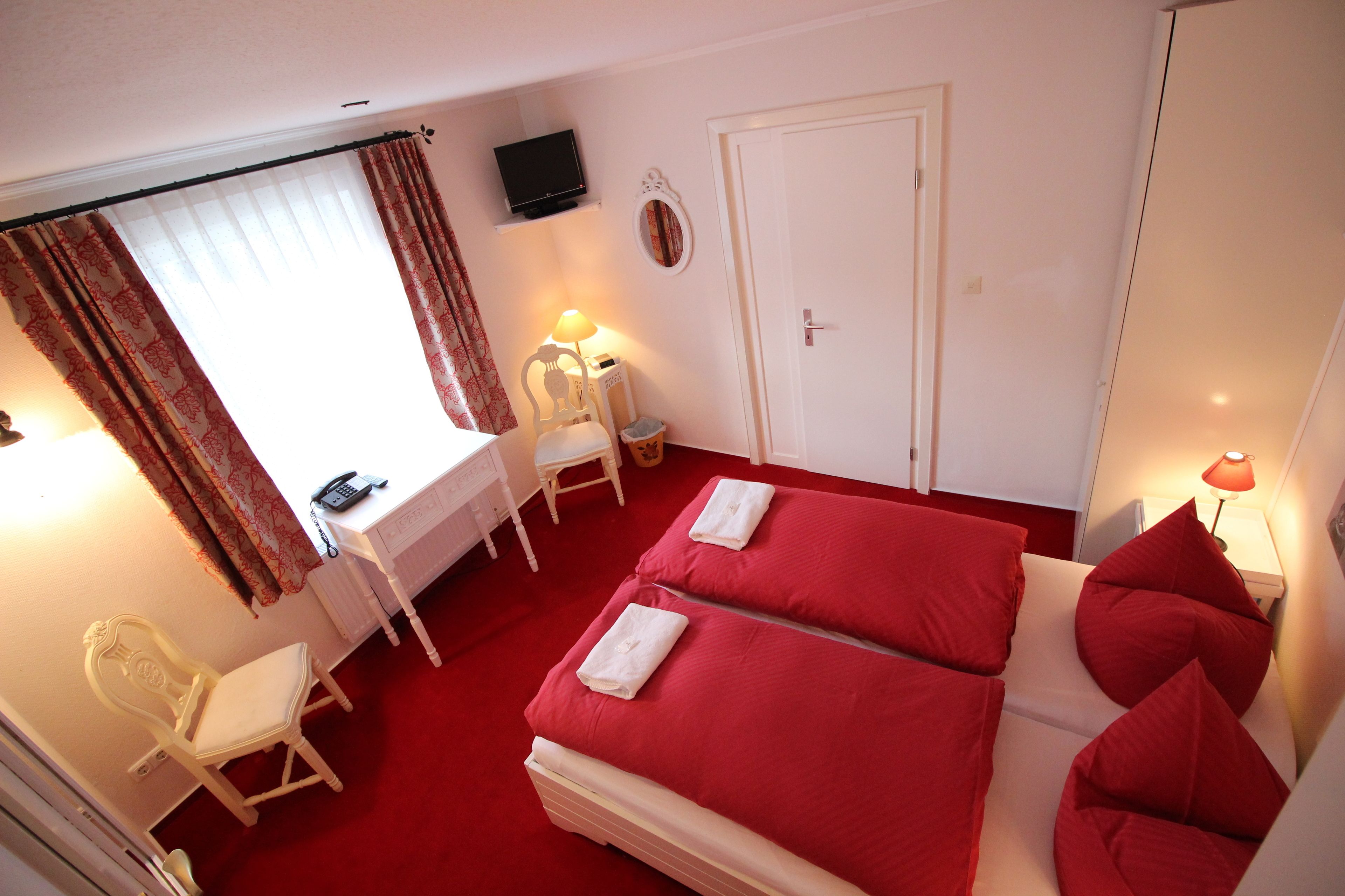 A room with two beds, a desk, a chair, a TV, and a door.