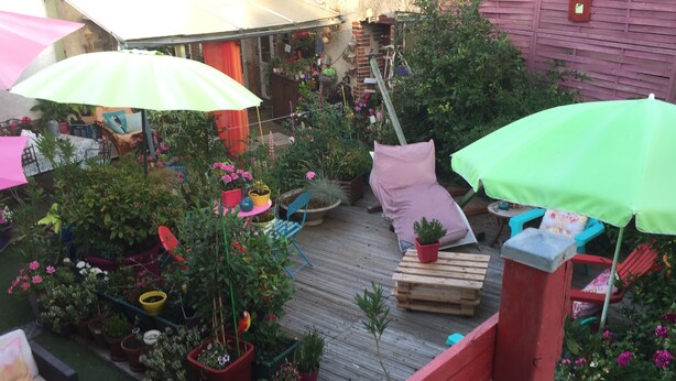 Une terrasse en bois agrémentée de plantes en pot et de mobilier d’extérieur.