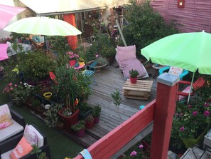 Une terrasse en bois agrémentée de plantes en pot et de mobilier d’extérieur.