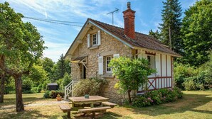 A stone house with a chimney, a wooden deck, and a picnic table. - La Petite Affolante, charming residence in Samois Sur Seine (Samois Sur Seine)