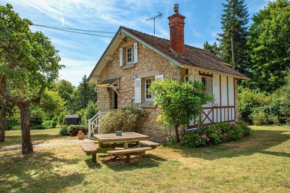 Una casa in pietra con un camino, un pontile in legno e un tavolo da picnic.