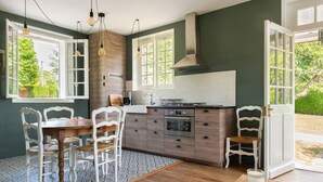 A modern kitchen with a central island, white chairs, and a view of greenery outside. - La Petite Affolante, charming residence in Samois Sur Seine (Samois Sur Seine)