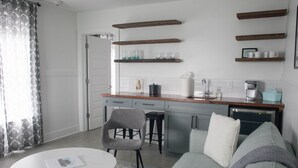 Eine moderne Küche mit Holzböden, einer Kaffeemaschine und einem Essbereich mit Tisch und Stühlen.