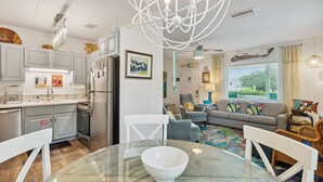 A modern kitchen with white cabinets, stainless steel appliances, and a glass dining table.