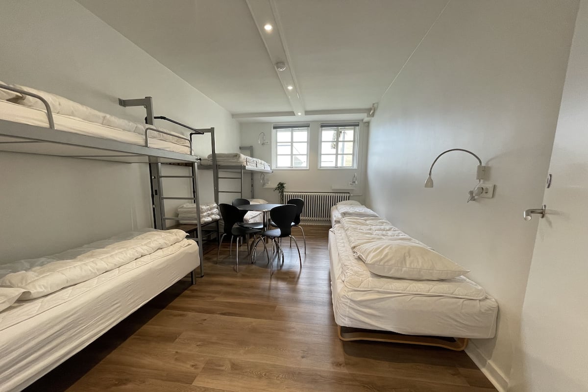 Un dormitorio con literas, una mesa con sillas y un radiador.