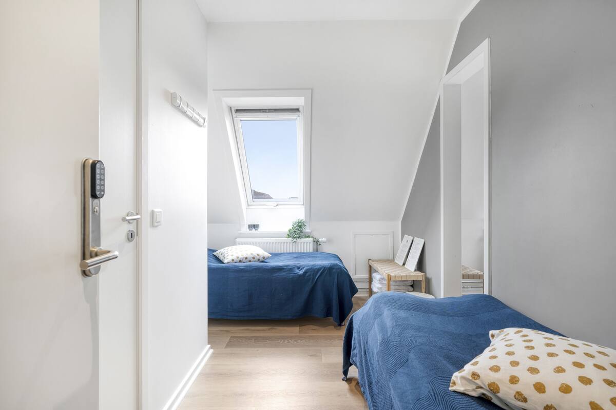 Un dormitorio con dos camas, una ventana y una puerta con cerradura.