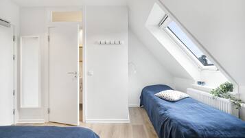 Ein Schlafzimmer mit zwei Betten, einem Oberlicht und einer weißen Tür zu einem Badezimmer.