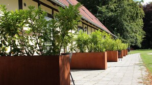 A row of planters with green foliage along a paved walkway. - Kragsbjerggaard Vandrerhjem (Odense)