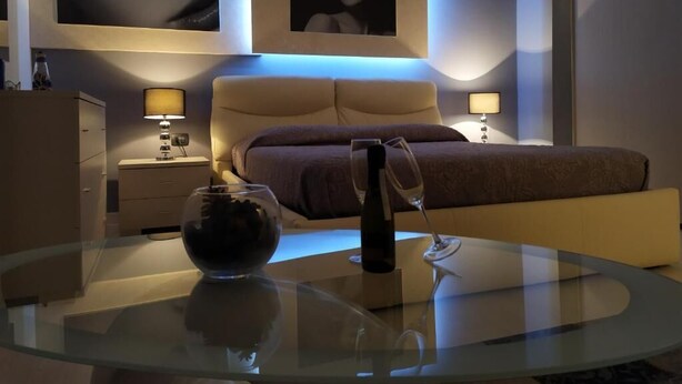A modern bedroom with a glass table, a wine bottle, and a wine glass. - Crocco d'oro (Caltavuturo)