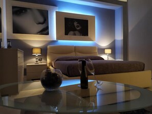 A modern bedroom with a glass table, a wine bottle, and a wine glass. - Crocco d'oro (Caltavuturo)