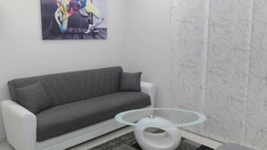 A modern living room with a grey sofa, a glass coffee table, and a painting on the wall. - Crocco d'oro (Caltavuturo)