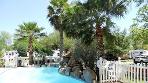 A pool area with palm trees, a white picket fence, and RVs in the background. - ⭐Great4Stargazing ⭐ Steps2Lake ⭐ Perfect4Families ⭐Patio (Kingsland)