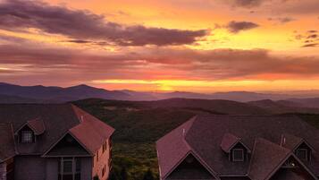 A view of a mountain landscape with a sunset, featuring a row of traditional houses with steep roofs.