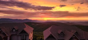 Une vue sur un paysage montagneux au coucher du soleil, avec une rangée de maisons traditionnelles aux toits pentus.