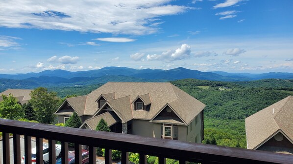 Une vue sur un paysage montagneux avec une maison dotée d’un toit à pignon et d’un balcon.