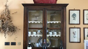 A wooden cabinet with glass doors displaying tea sets and wine bottles. - The paradise of relaxation, villa in the Langhe with panoramic views (Lequio Berria)