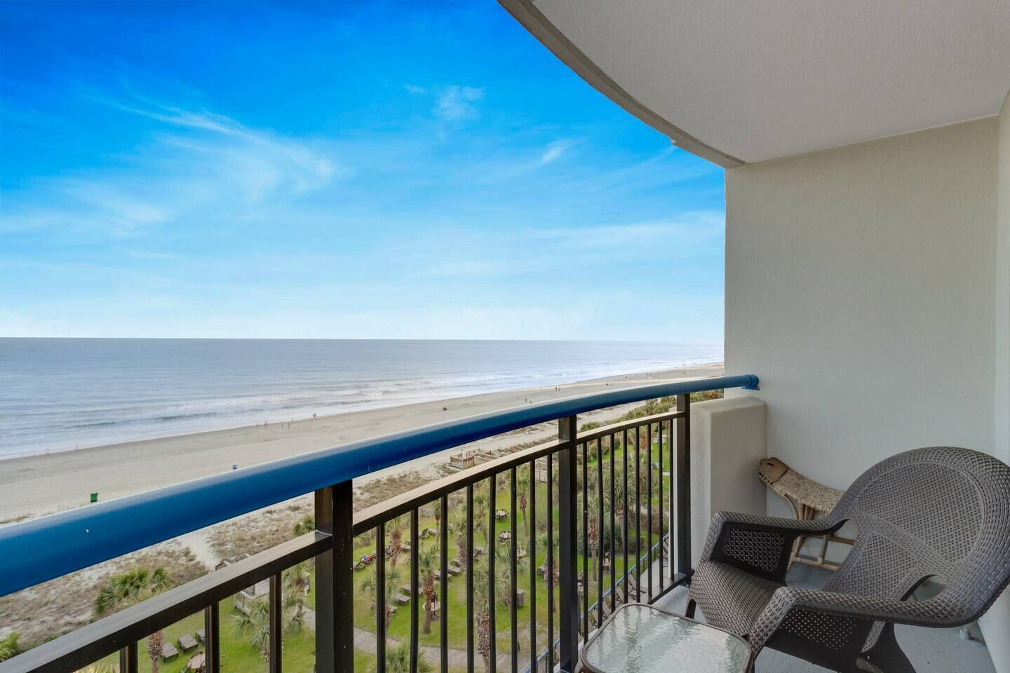 A balcony with a view of the beach and ocean.
